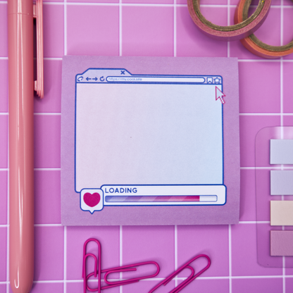 Pink sticky note pad with an internet browser loading screen design on a pink grid background with stationery items.