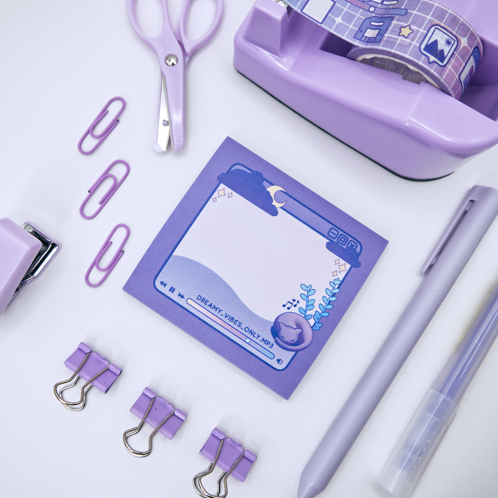 Purple sticky note pad with music player design featuring a cat and a plant surrounded by stationery items including a pen, scissors, and tape dispenser on a white background