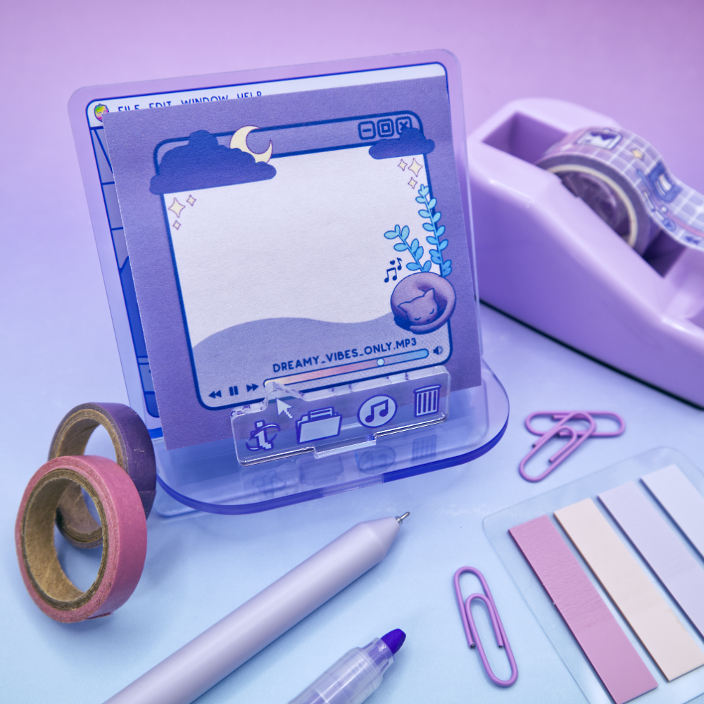 Purple sticky note pad with music player design featuring a cat and a plant, resting on an acrylic stand with a computer design on a purple background, surrounded by stationery items.