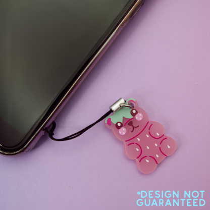 Pink strawberry-patterned bear-shaped phone charm attached to a phone on a purple background