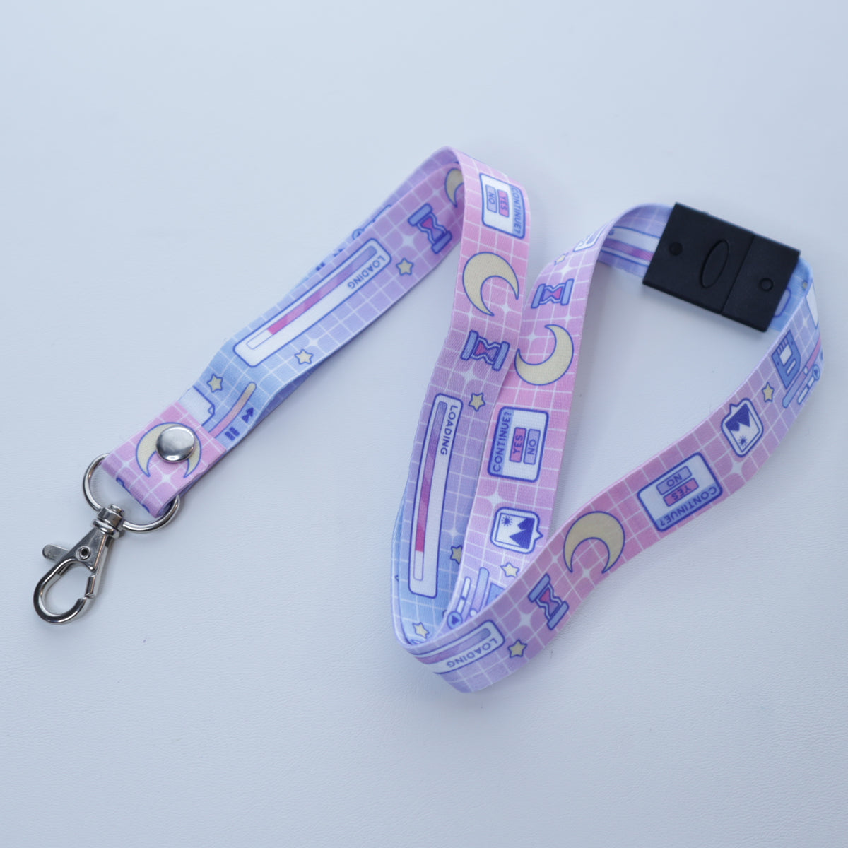 A pastel pink and blue computer UI patterned lanyard with a breakaway safety buckle and silver lobster clasp sits on a white background.  