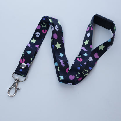 A black, early 2000's "scene kid" patterned lanyard with a breakaway safety buckle and silver lobster clasp sits on a white background. 