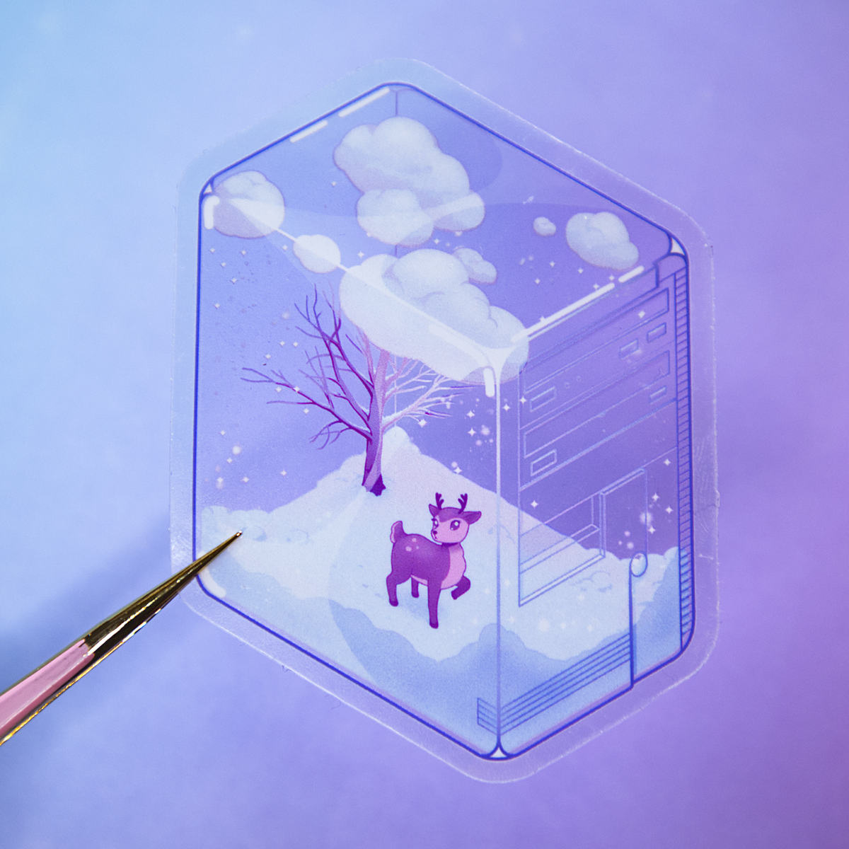 A pair of tweezers holds die-cut sticker featuring a winter scene with a small deer, bare tree, and snow, inside of a translucent PC tower like a snow globe.  Sticker is photographed on a purple background.