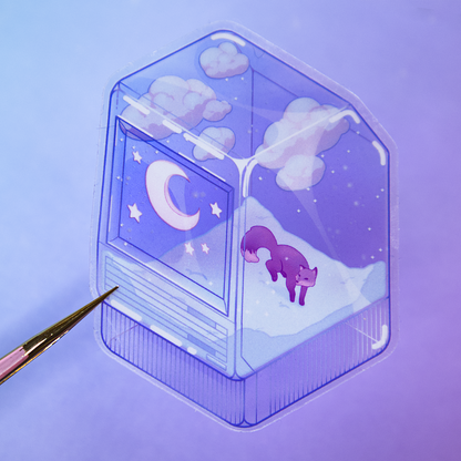 A pair of tweezers holds die-cut sticker featuring a winter scene with a small fox, night sky, and snow, inside of a translucent PC tower like a snow globe.  Sticker is photographed on a purple background.